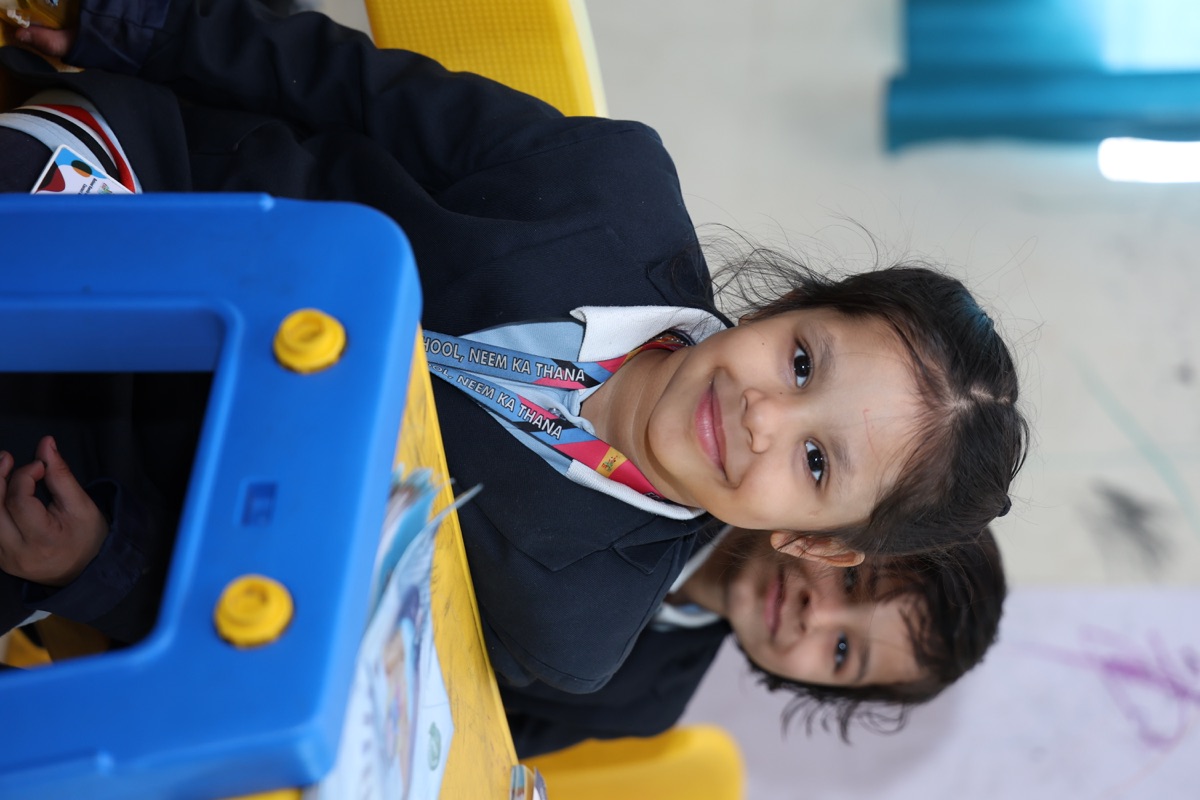 Children writing in notebooks at a bright classroom table